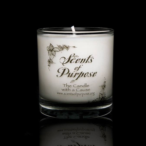 A white candle in a clear glass candle holder by Scents of Purpose on a black background. 
